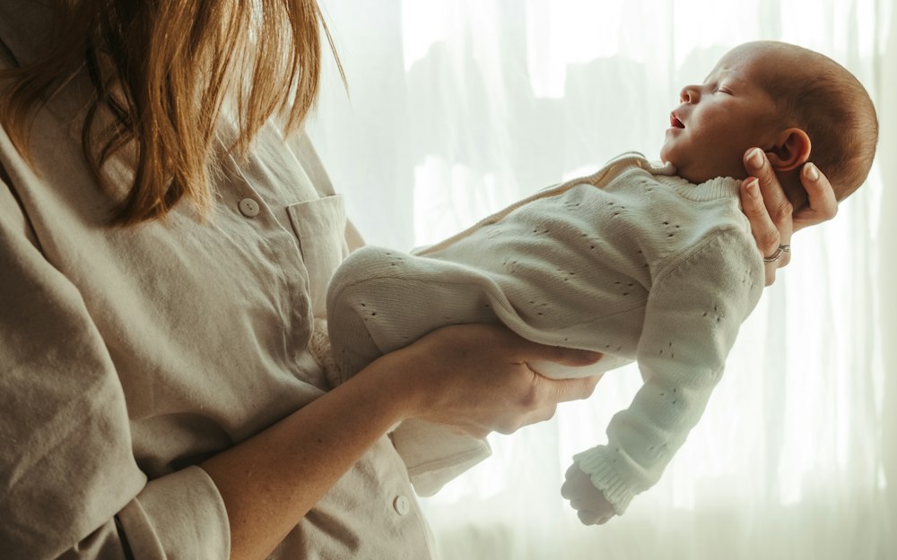 Mother holding her newborn baby by a window